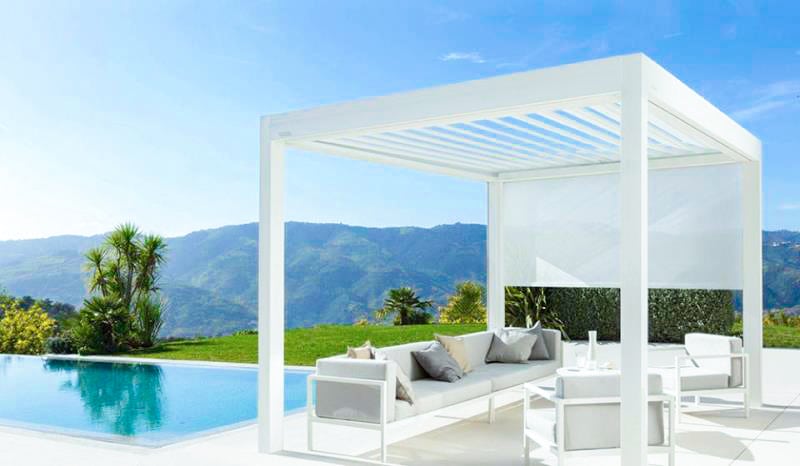Weißes Pergola-Lamellendach mit Sichtschutz-Screen, Loungesofa und Pool vor Bergpanorama