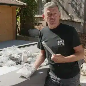 Mann in schwarzem T-Shirt, der verschiedene Materialien in Plastiktüten auf einem Tisch präsentiert. | my-pergola24.com