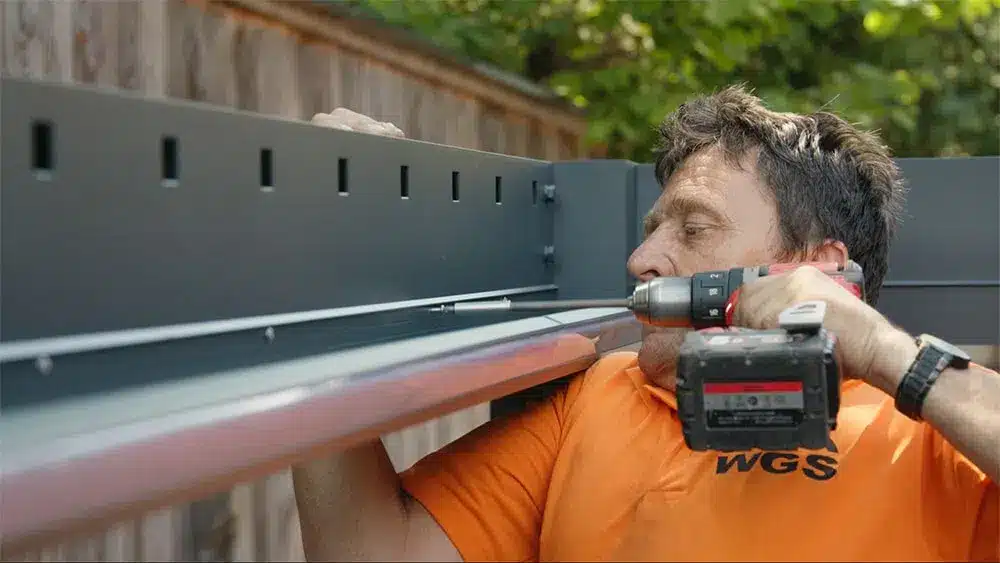 Mann mit einem Akku-Schrauber, der eine Konstruktion montiert, während er konzentriert arbeitet. | my-pergola24.com