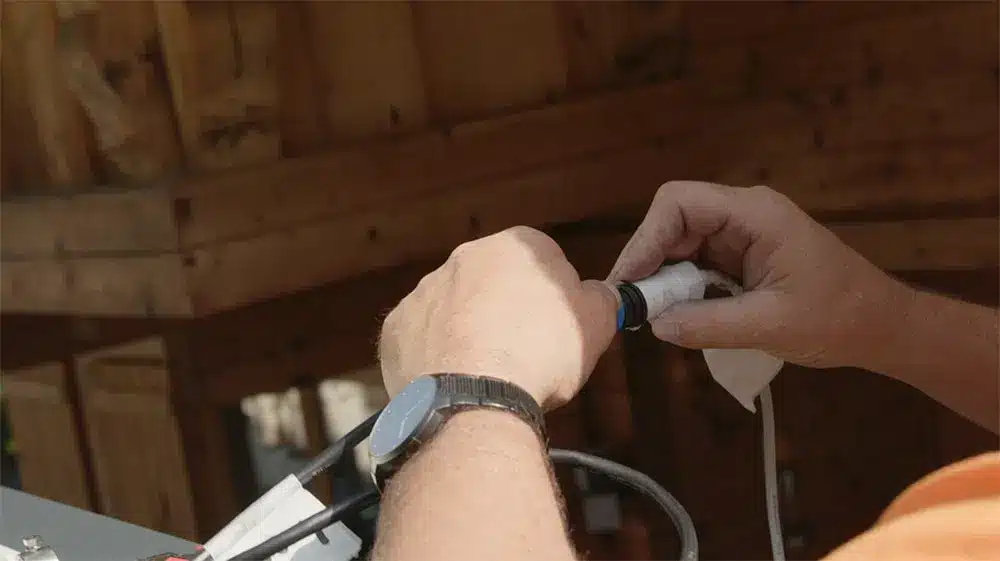 Techniker mit einer Hand, die an einem Kabel arbeitet, während er eine Installation durchführt. | my-pergola24.com