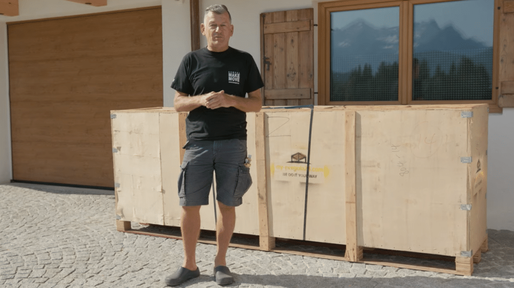 Heimwerkerkönig Mark Kühler vor der Holzkiste mit seinem gelieferten Lamellendach