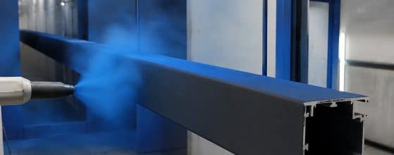 Ein schwarzes Aluminium-Pergolaprofil wird in einer Lackierkammer mit blauem Pulver beschichtet. | my-pergola24.com