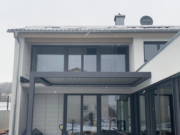 Dunkles Lamellendach an der Hauswand vor einer großen Fensterfront