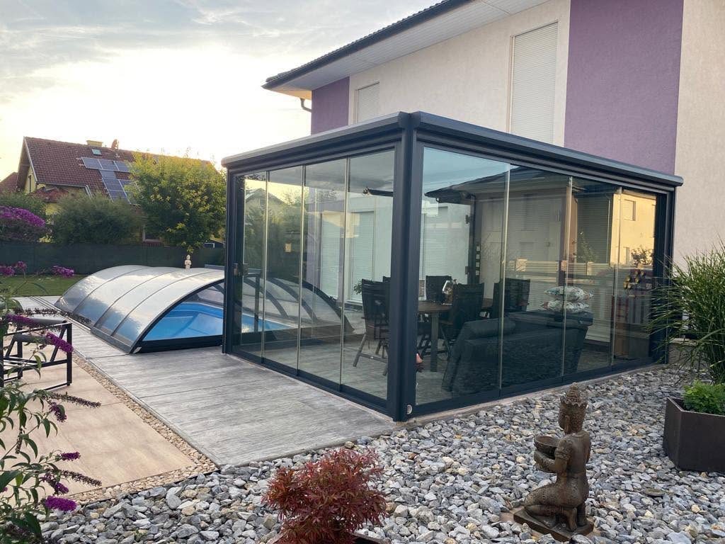 Glaspavillon mit Lamellendach am Haus, daneben eine Poolüberdachung und ein Kiesgarten