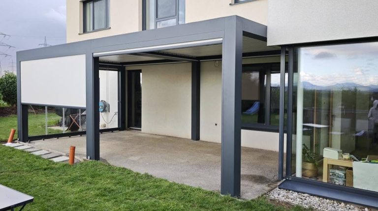 Anthrazitfarbenes Lamellendach mit Glaswand an einem modernen Haus mit großen Fenstern
