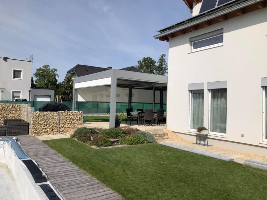 Graue Pergola am Haus mit Gabionen und abgedecktem Pool im Garten