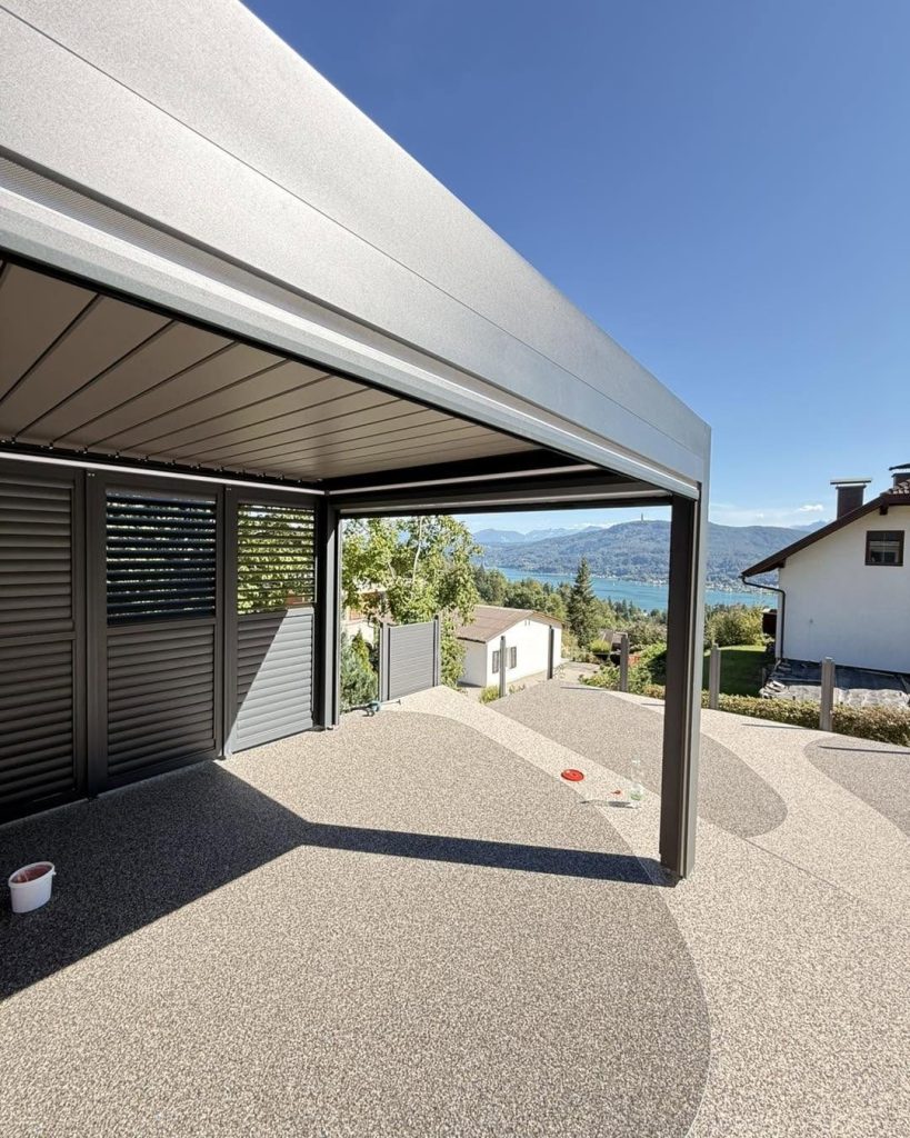 Lamellendach in Techelsberg am Wörthersee mit grauer Lamellenwand auf einer Terrasse mit Steinteppich und weitem Blick