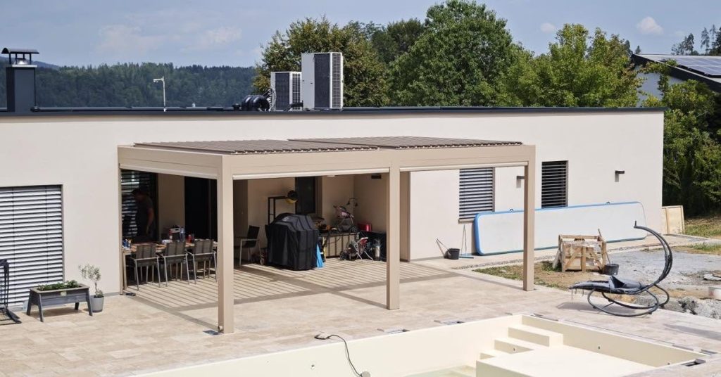 Beigefarbenes Lamellendach in Köflach mit Terrasse und Liegestuhl vor einem weißen Haus