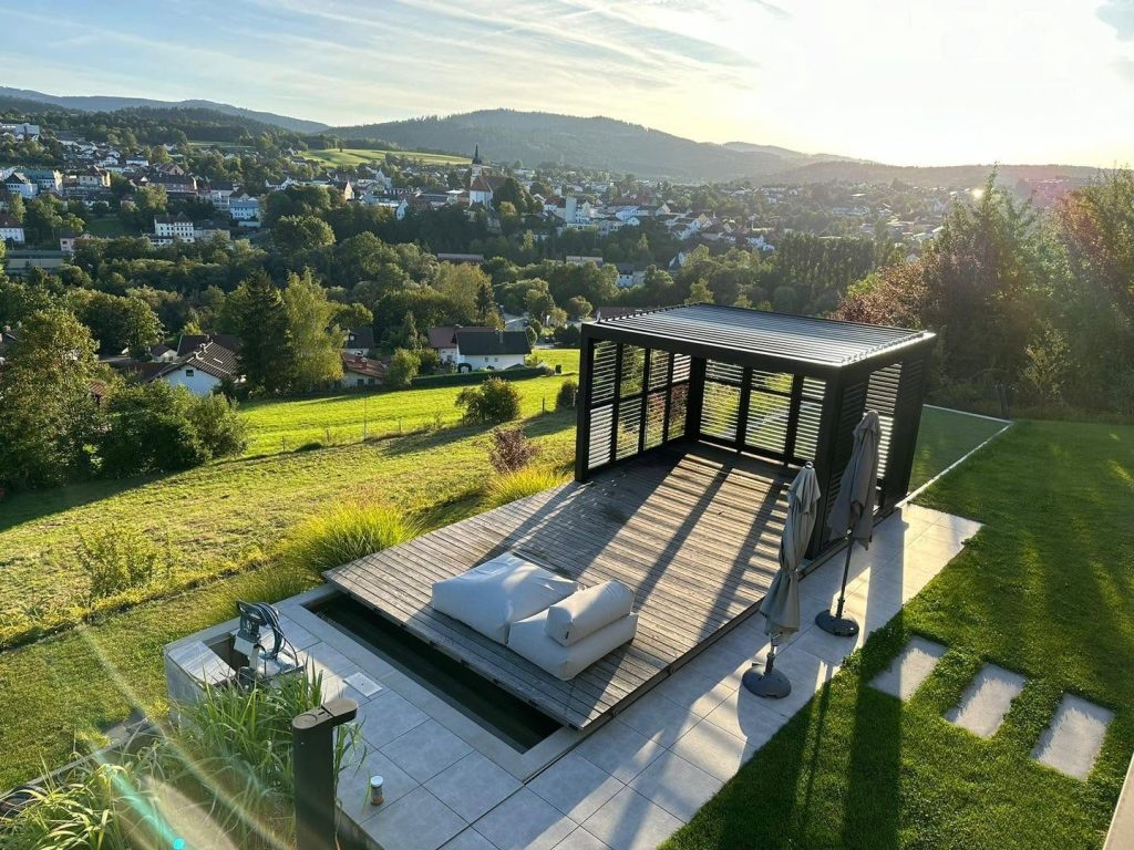 Pavillon in Bayern mit Lamellendach und Liegefläche auf einer Terrasse in Hanglage mit weitem Blick