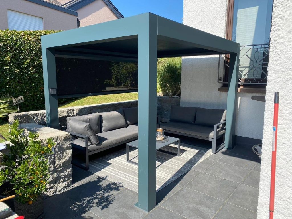 Türkisfarbene Pergola mit Sitzgruppe auf einer Terrasse mit Steinmauer