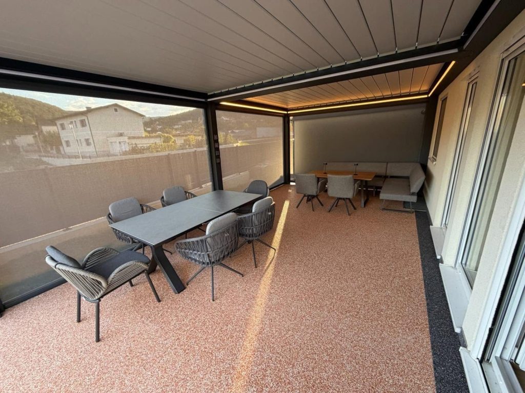 Überdachte Terrasse mit Esstisch und Stühlen unter einem Lamellendach mit Seitenscreen