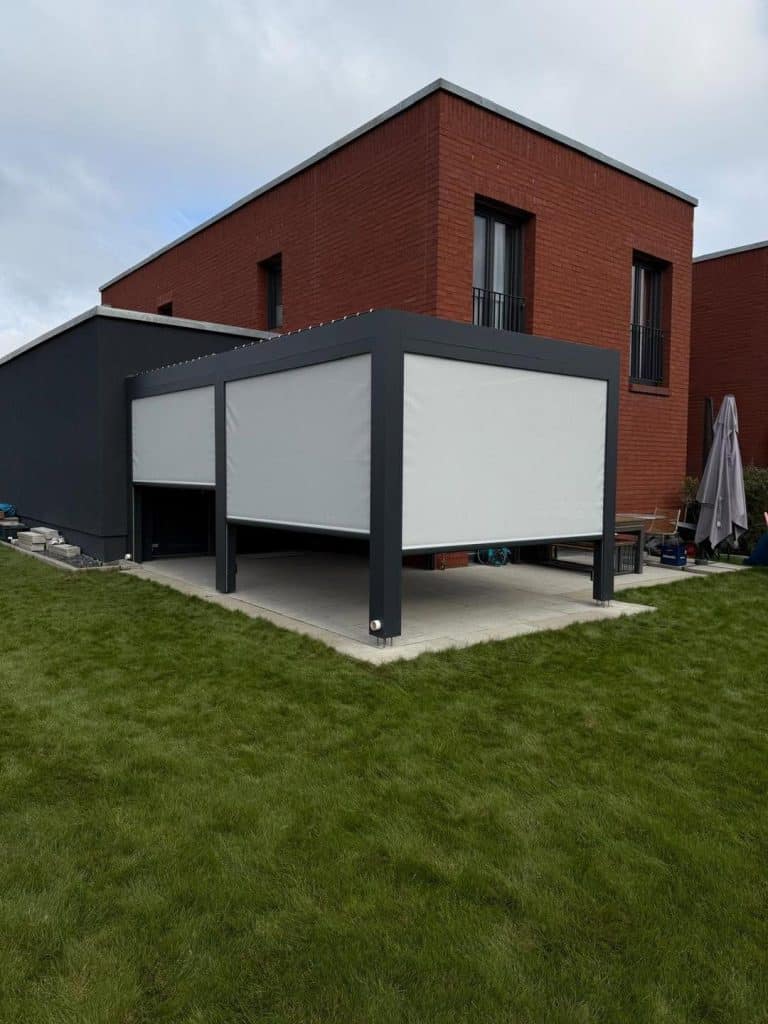 Lamellendach mit weißem Screen an einem Haus aus rotem Klinker, davor ein Rasen